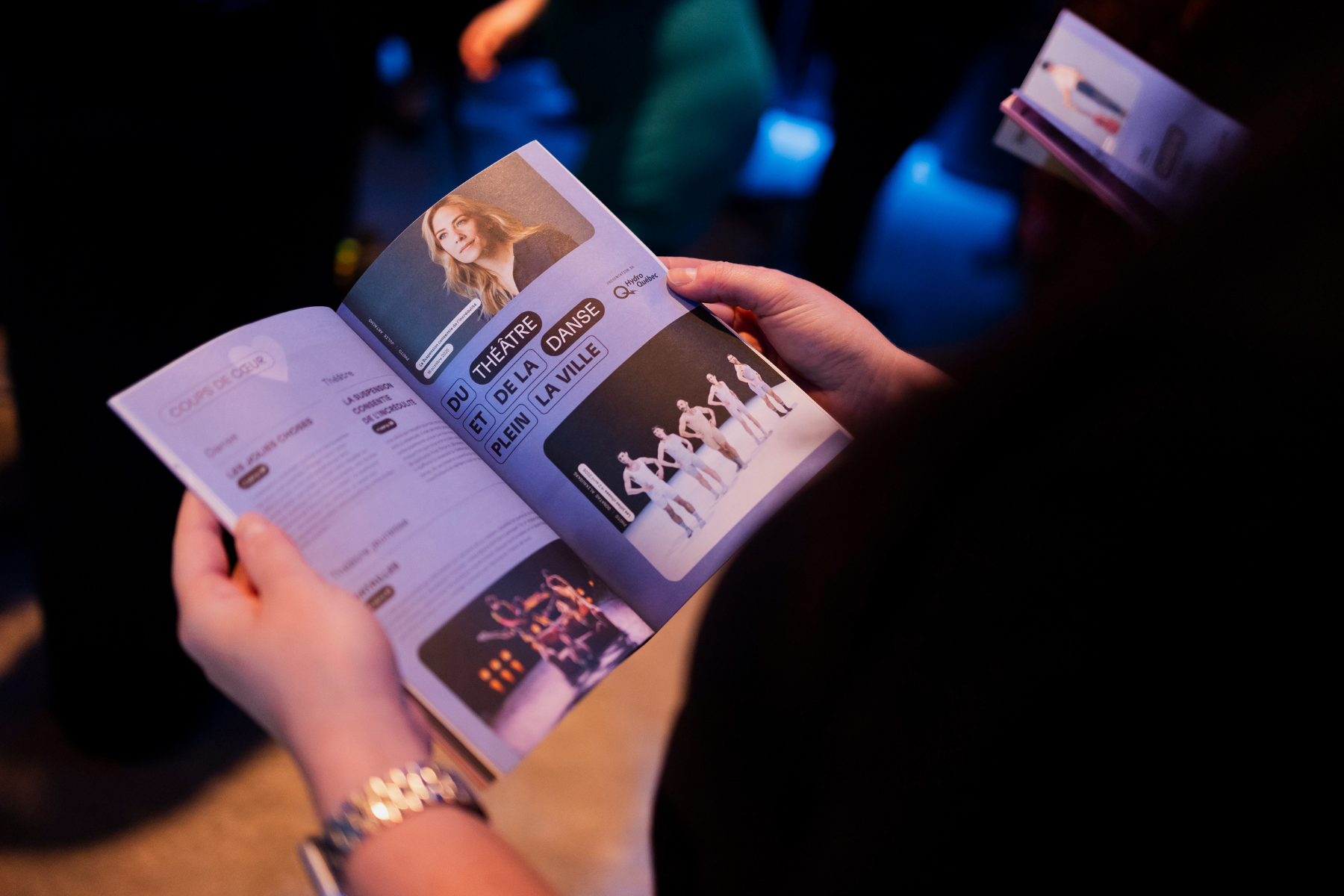 Gros plan sur une brochure de programmation tenue dans les mains d'une personne qui planifie sa saison culturelle